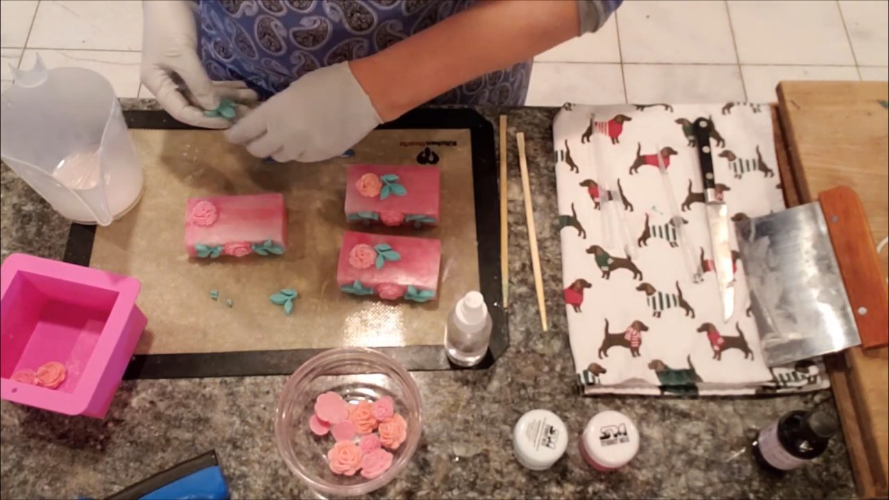 Gluing extra rose and leaf embeds onto the soap bars with melted soap