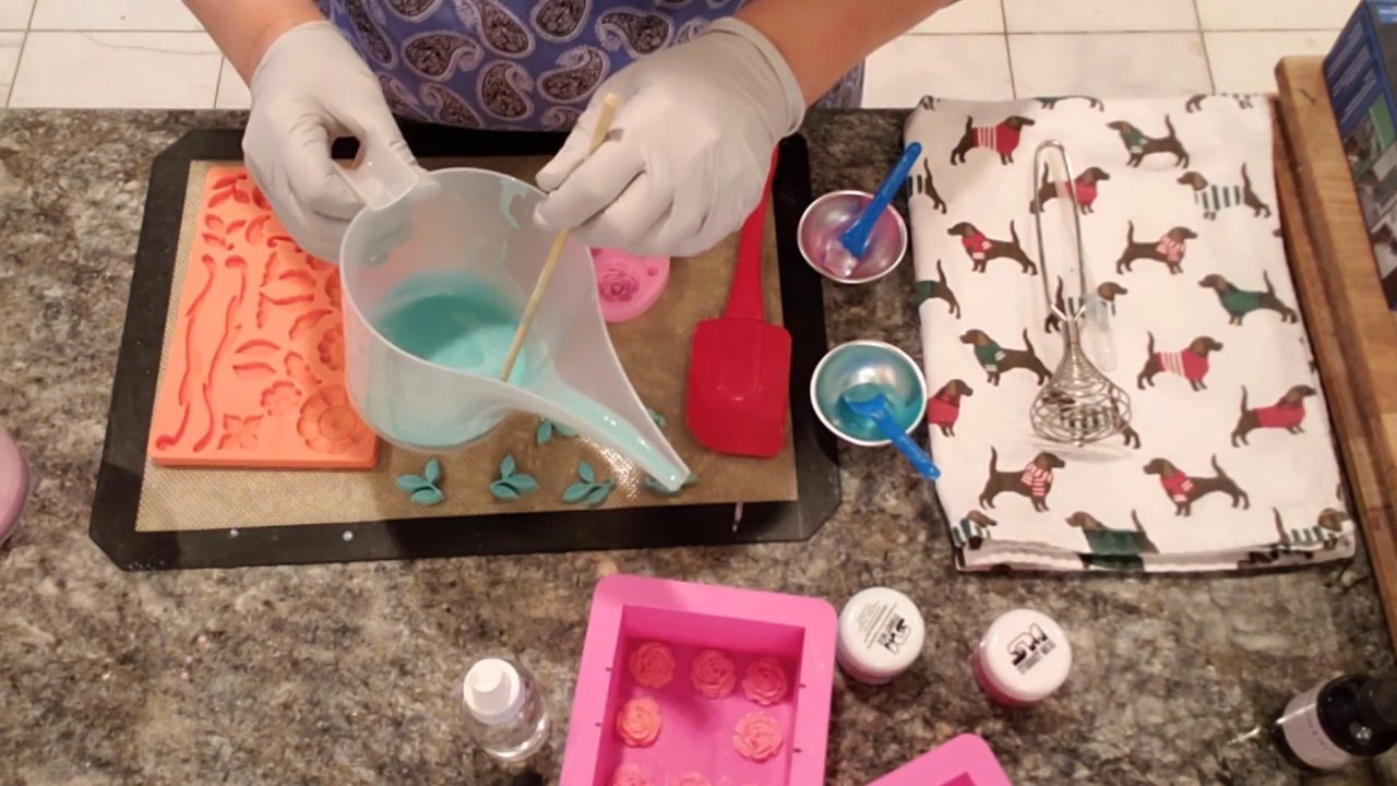 Pouring green shea butter soap into a leaf fondant mold