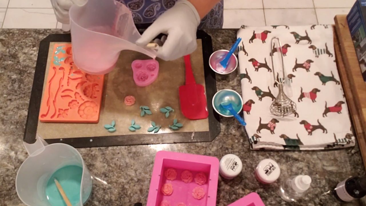 Pouring pink soap into small rose molds