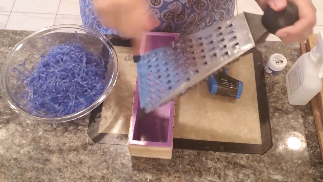 Grating blue soap into shreds with a cheese grater
