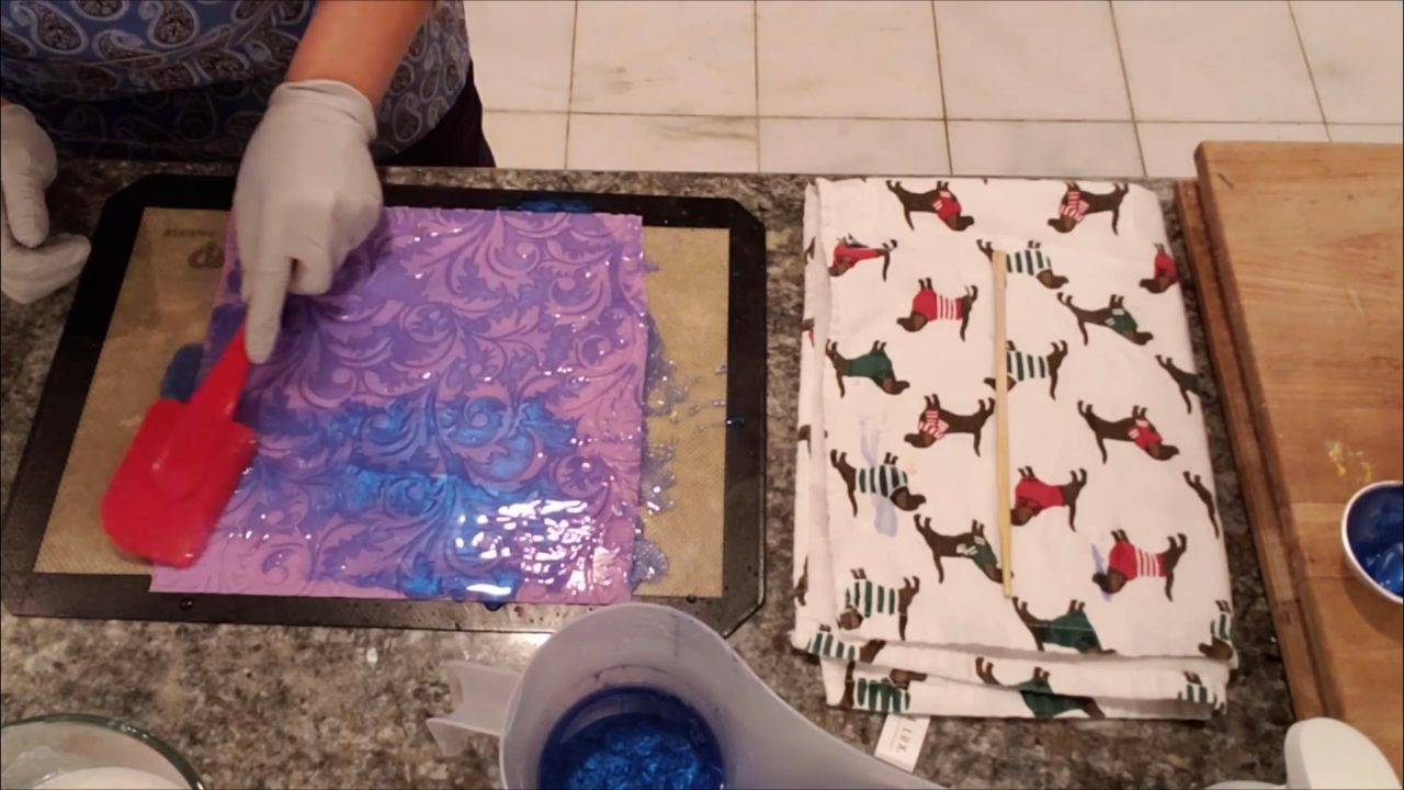 Spreading blue clear soap over an impression mat with a rubber spatula