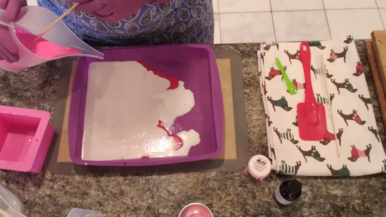 Pouring light pink shea butter soap as the top layer