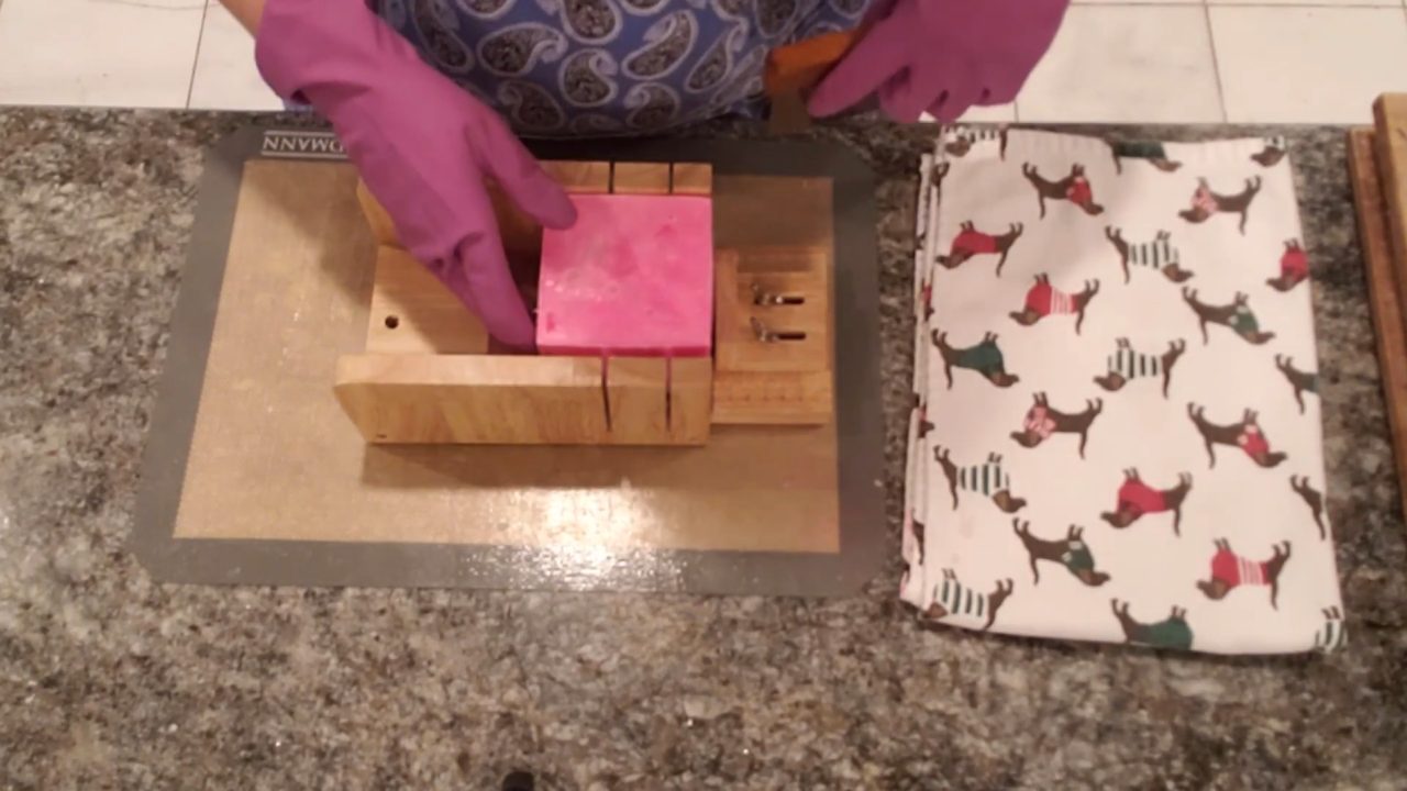 Unmolded candy stripe swirl soap loaf in a soap cutter