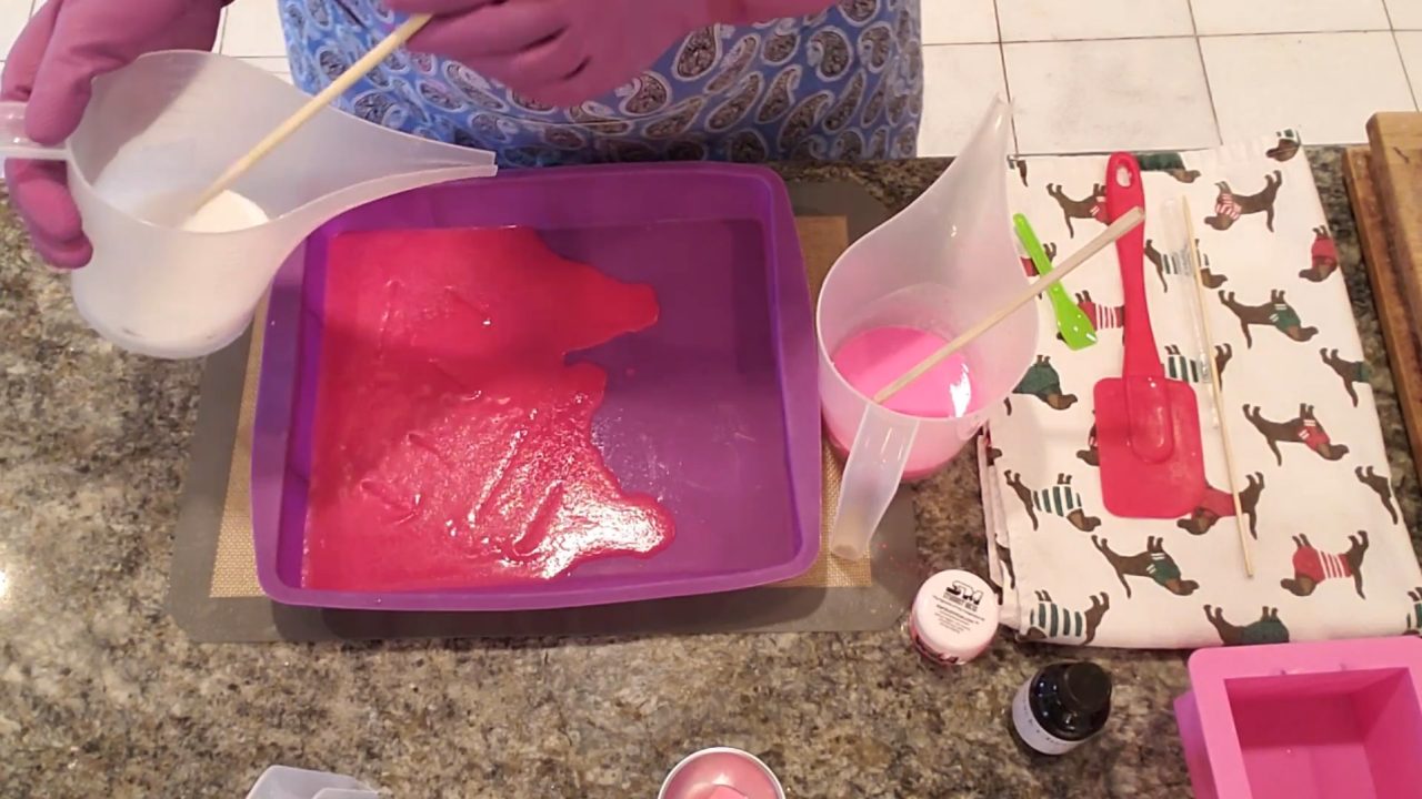 Pouring white shea butter soap over the pink layer