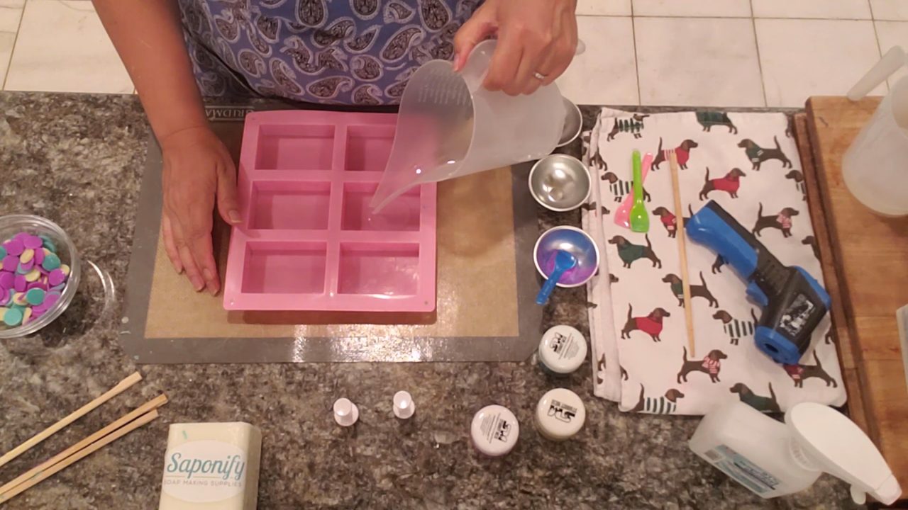 Pouring a thin clear layer into a pink 6 cavity soap mold