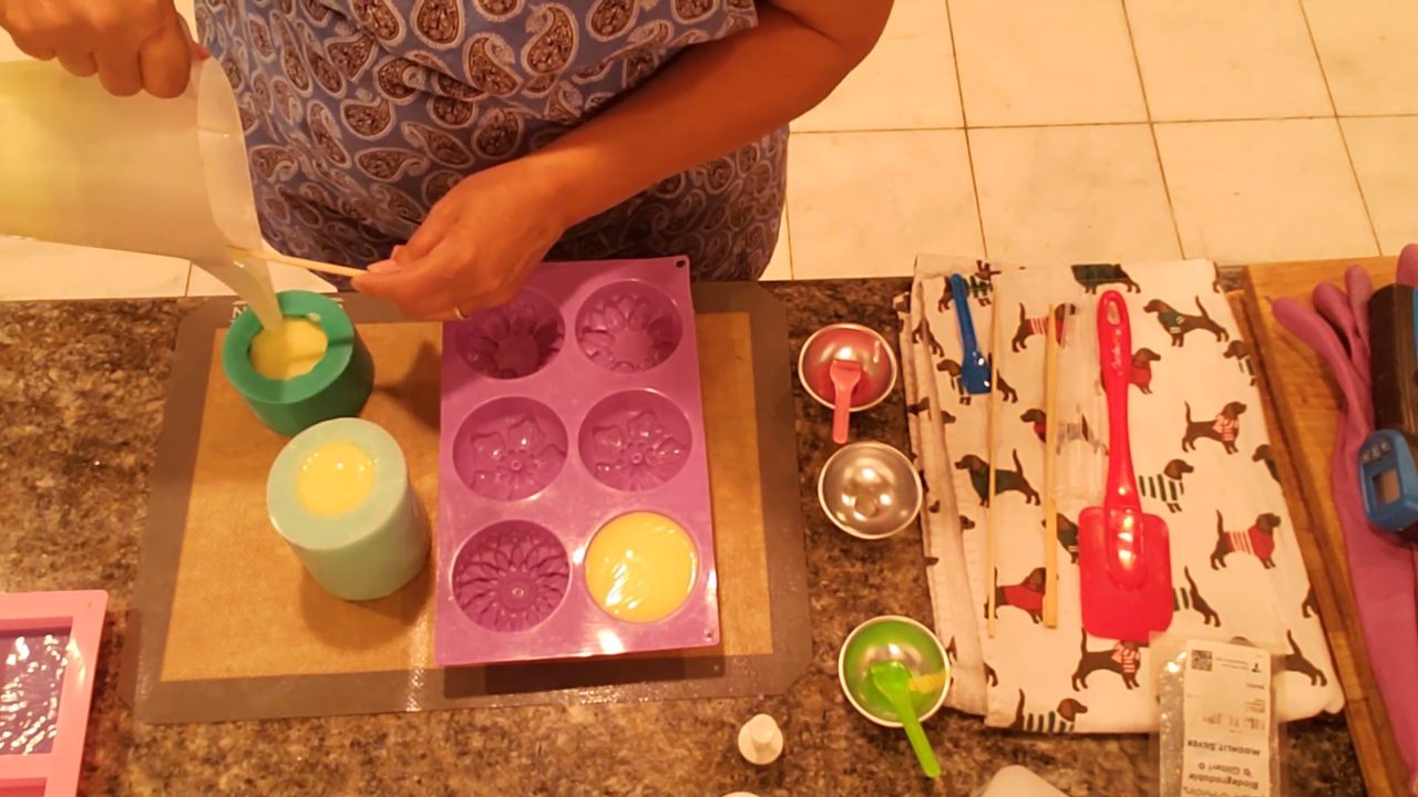 Pouring yellow soap over the purple frosting in the cupcake mold