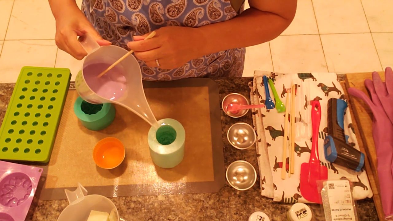Pouring purple frosting soap into a cupcake top mold