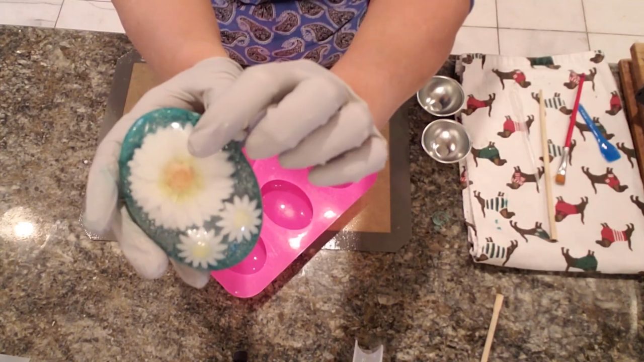 Finished daisy flower embed melt and pour soap with a teal glitter background