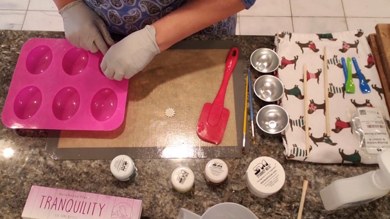 Placing daisy soap embeds face down into a pink oval silicone mold