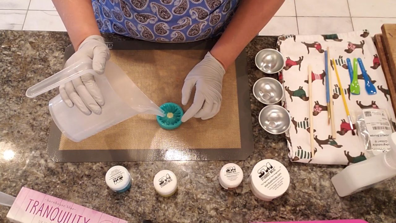 Pouring white shea butter melt and pour soap over the daisy mold