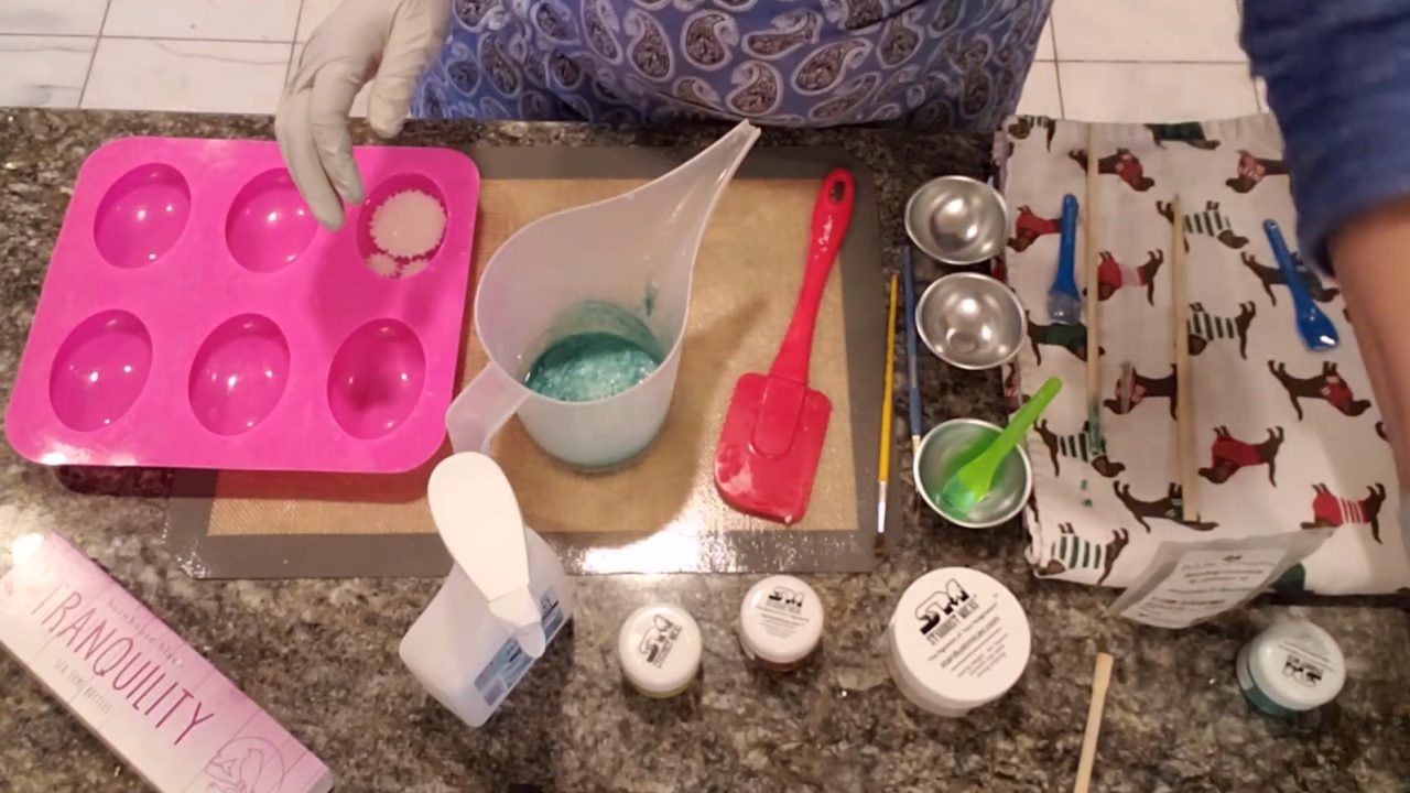 Pouring teal melt and pour soap with bio glitter over the daisy embeds