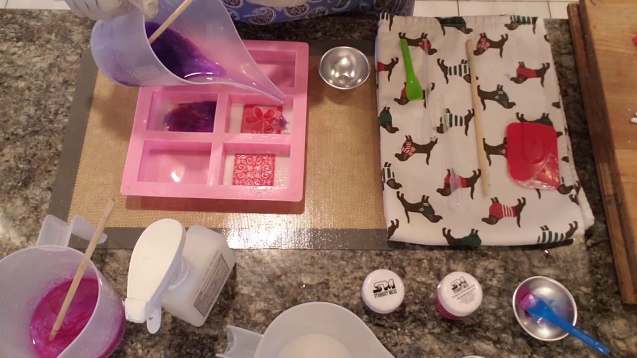 Pouring pink and purple mica-colored clear melt and pour soap into the mold
