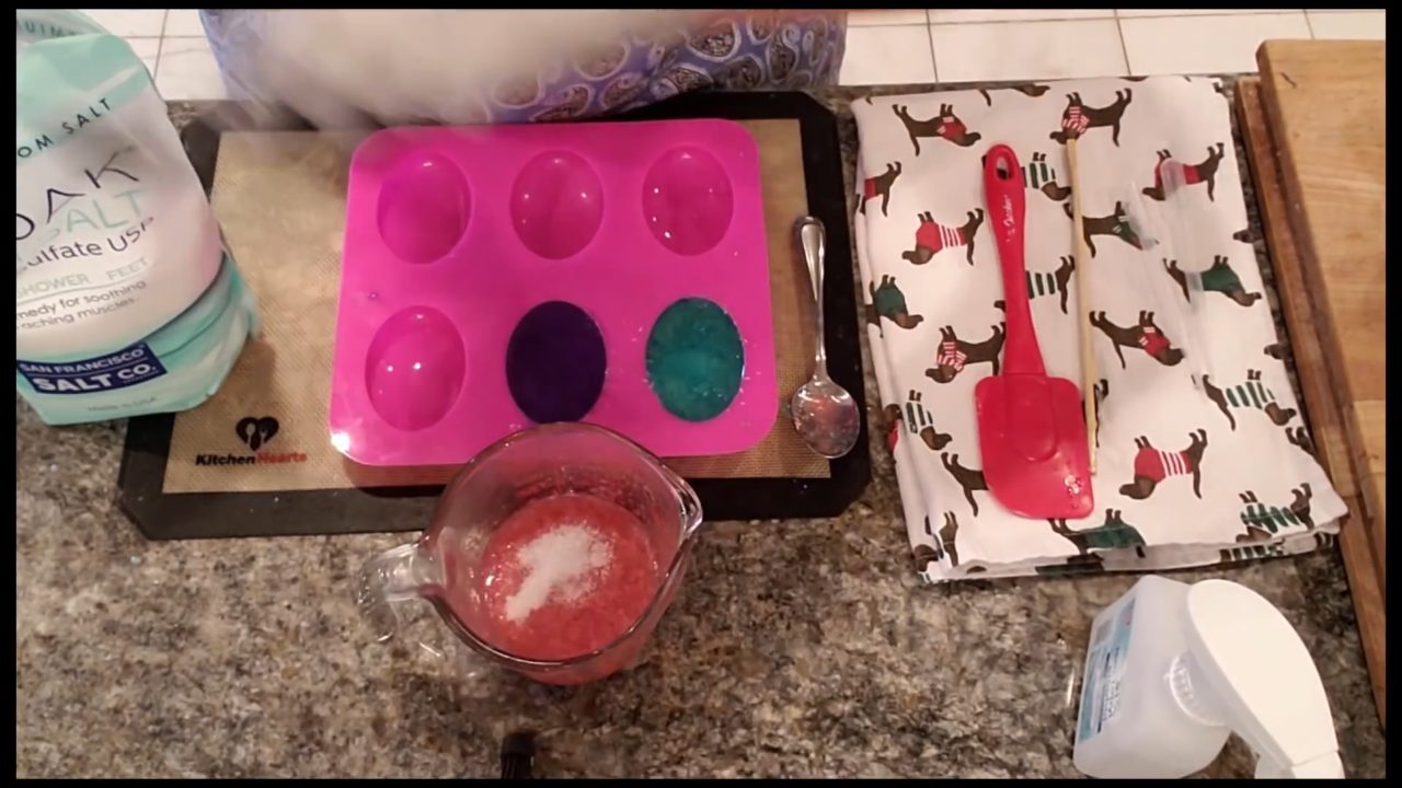 Mixing Epsom salt into pink melted soap in a cup until it looks like wet sand