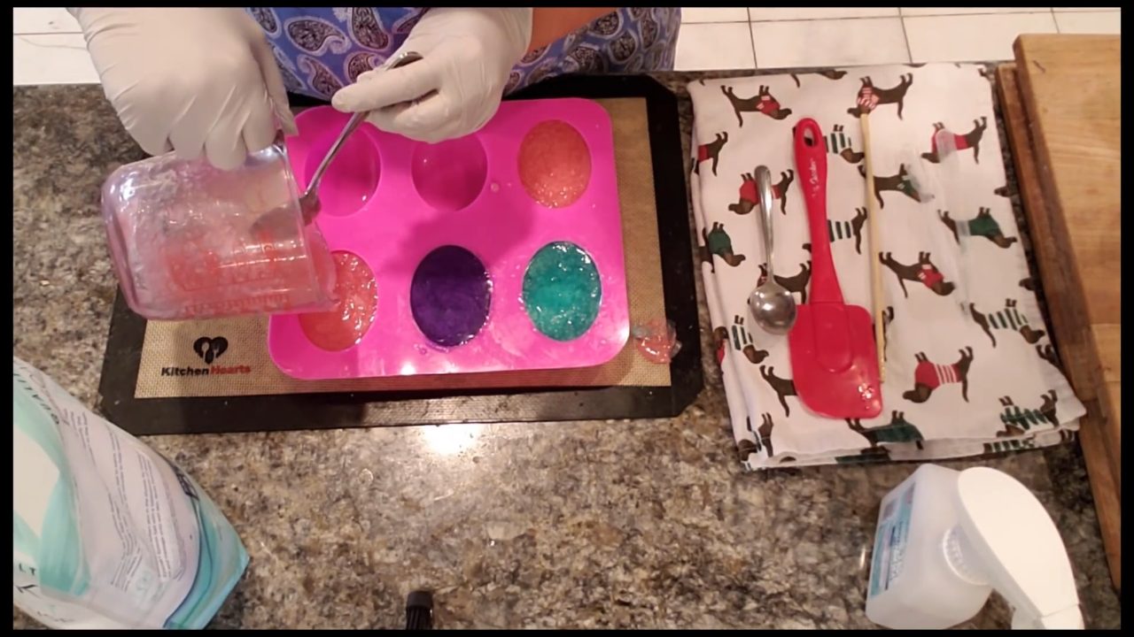 Pouring the pink Epsom salt soap mixture into the mold