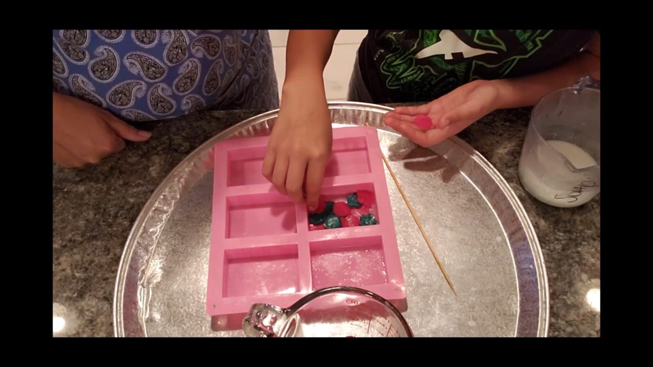 Placing small flower soap embeds face down on the clear soap layer