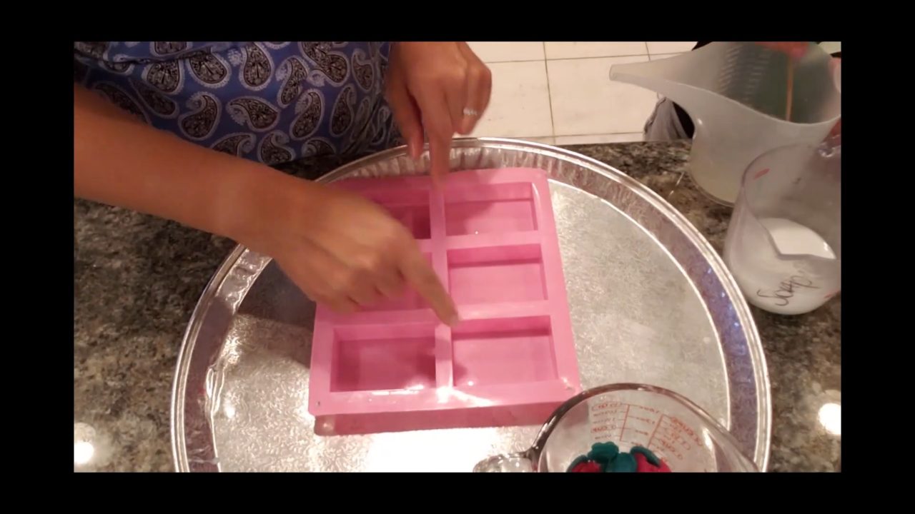 Pouring a thin layer of glittered crystal clear soap into a pink bar mold