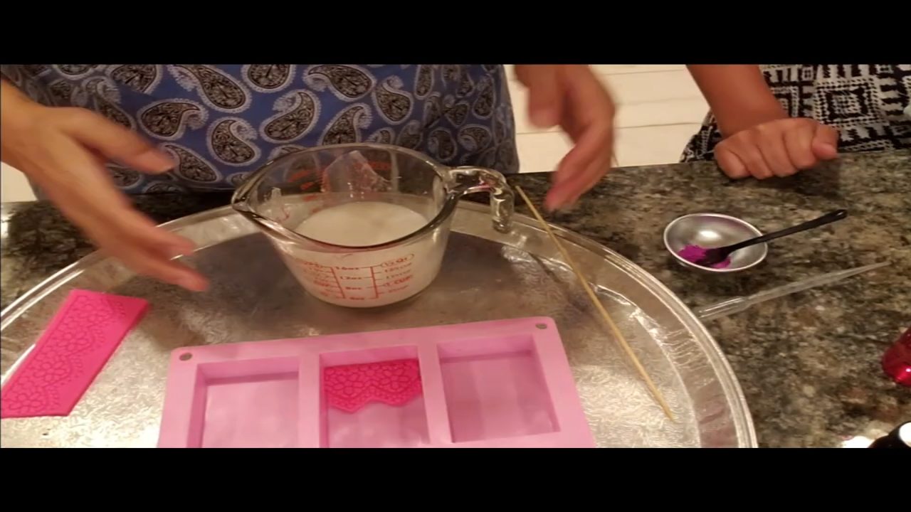 Gluing a cut fondant lace mat into the soap mold with melted soap