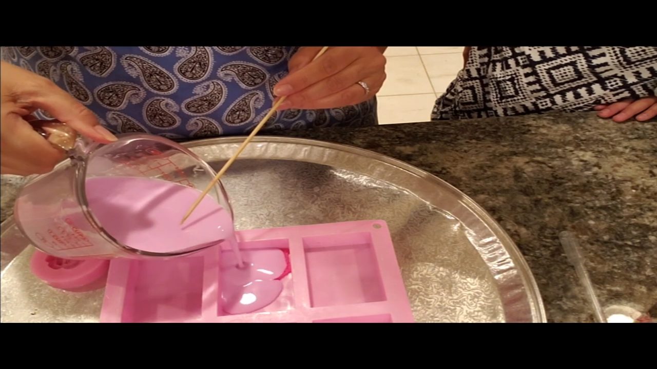 Pouring pink goats milk soap over the fondant lace mat