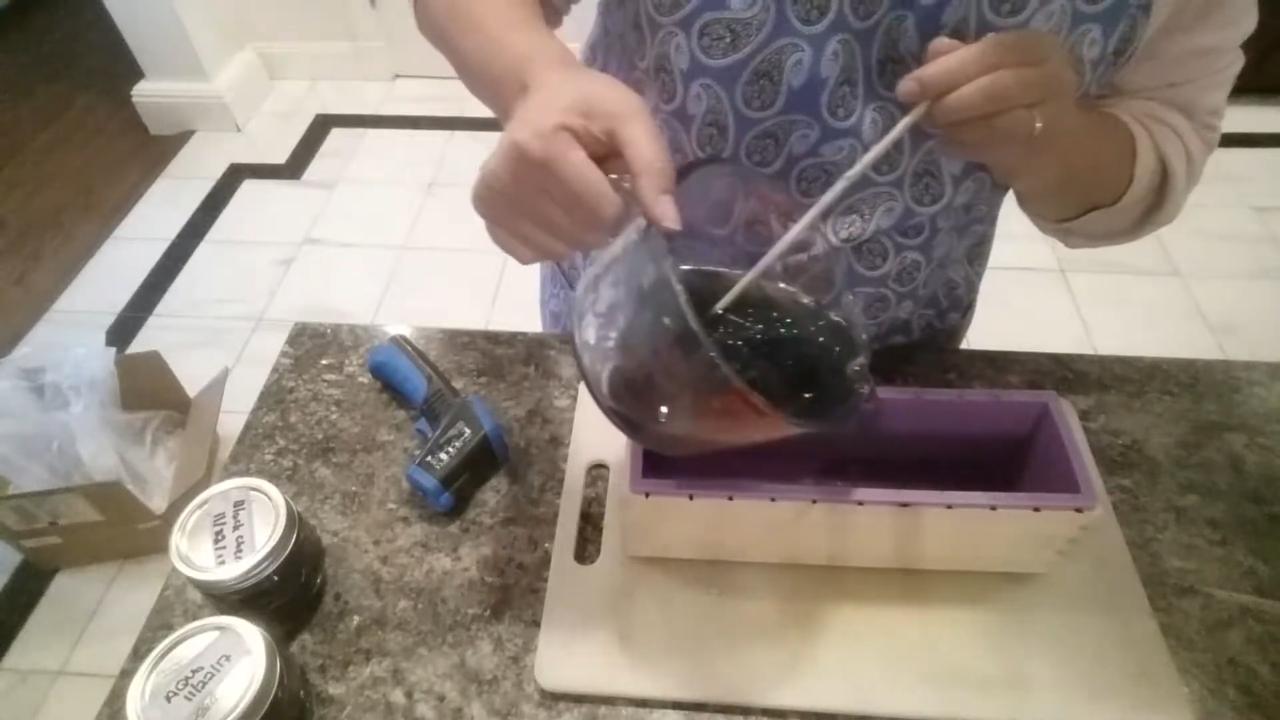 Pouring black glitter galaxy soap into a loaf mold