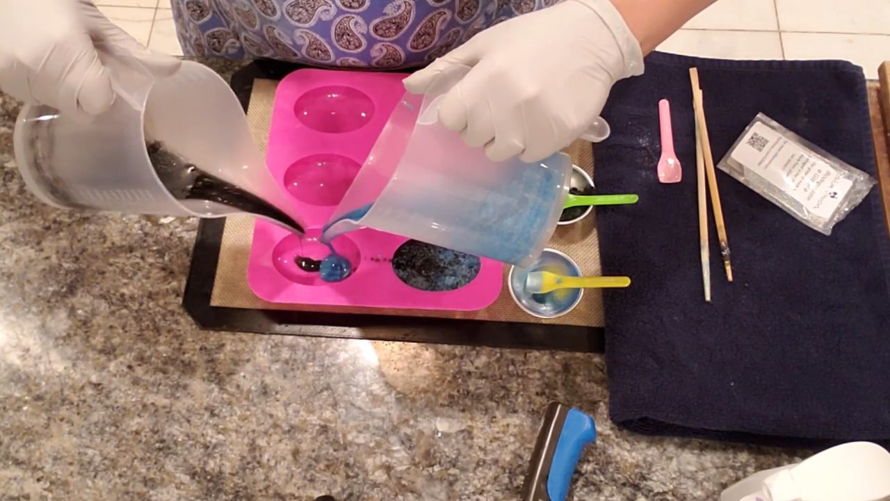 Pouring black and blue glitter soap together into an oval mold