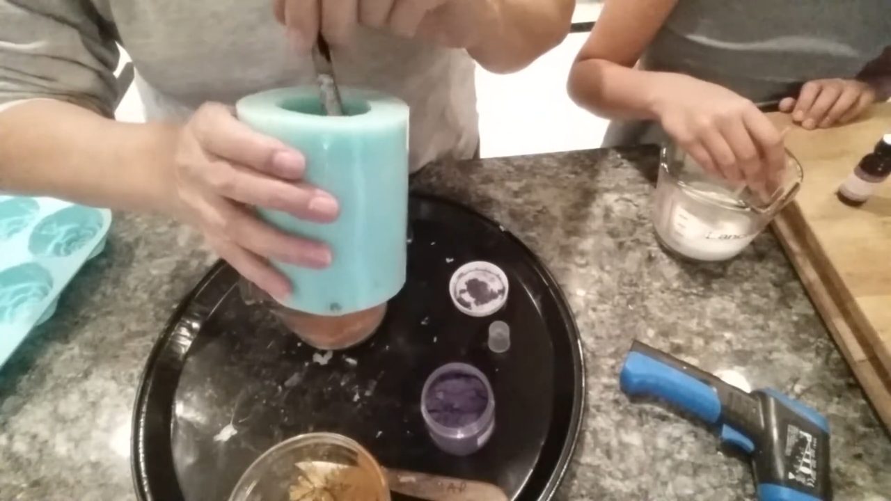 Brushing purple mica inside the top of a giant cupcake silicone mold