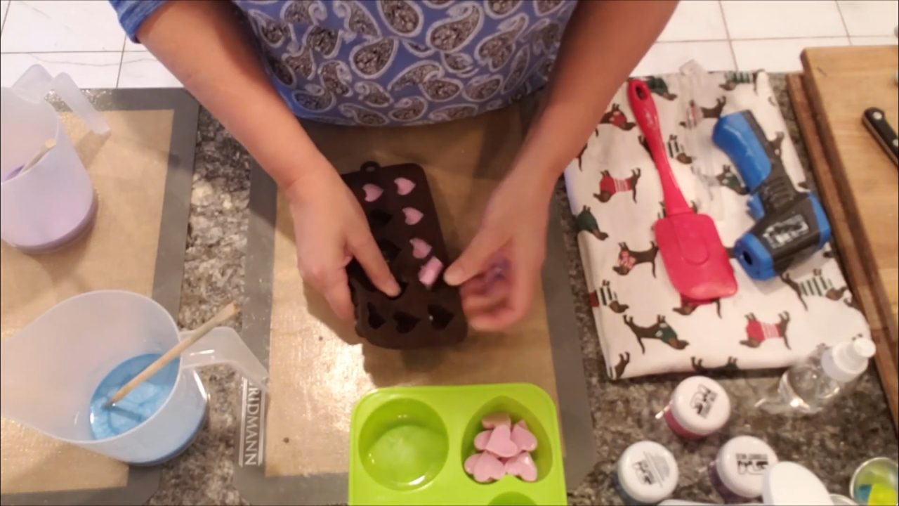Filling a heart mold halfway with blue soap for embeds