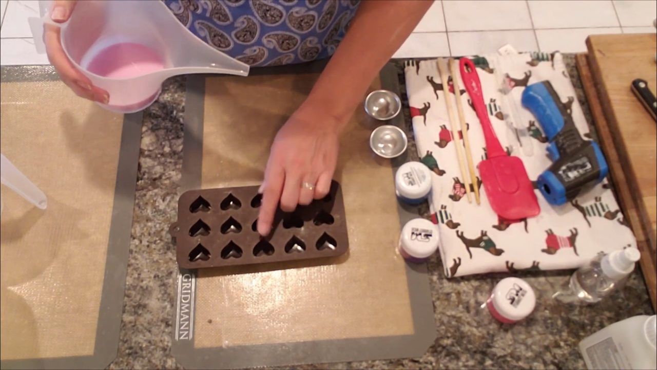 Pouring pink shea butter melt and pour soap into a small heart mold