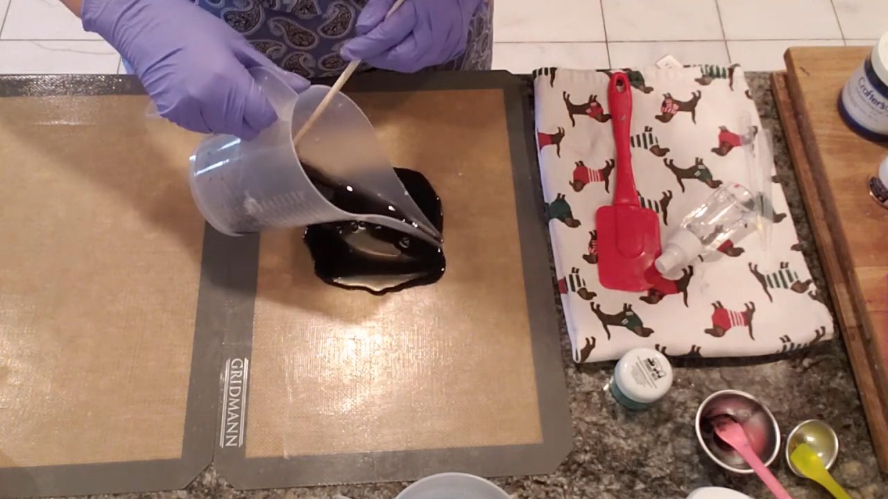 Pouring activated charcoal black melt and pour soap onto a silicone mat