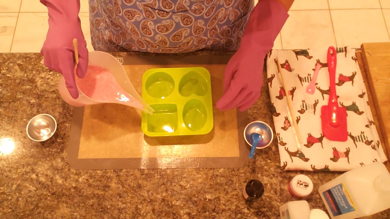 Pouring jojoba bead soap into a green silicone mold