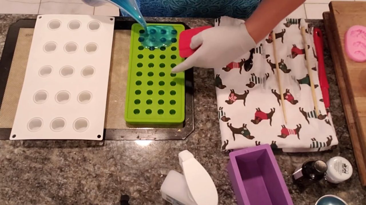 Pouring blue clear soap into a small ball silicone mold