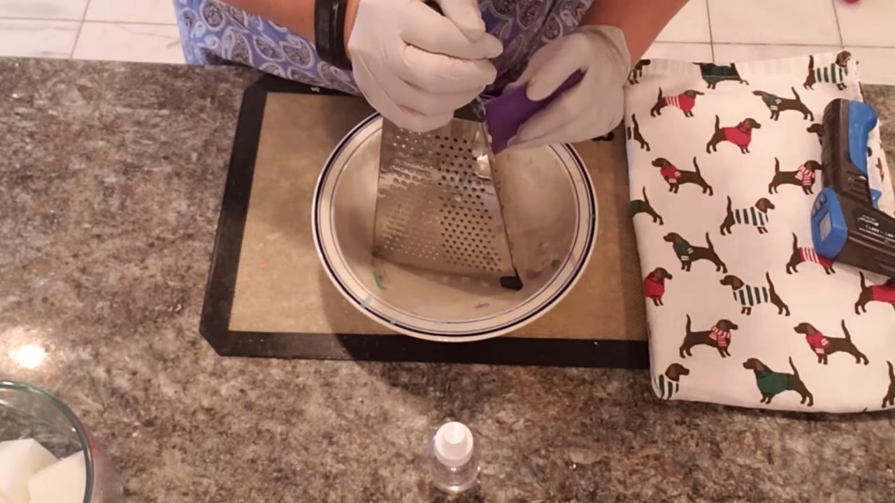 Grating purple, yellow and green clear soap into confetti shreds