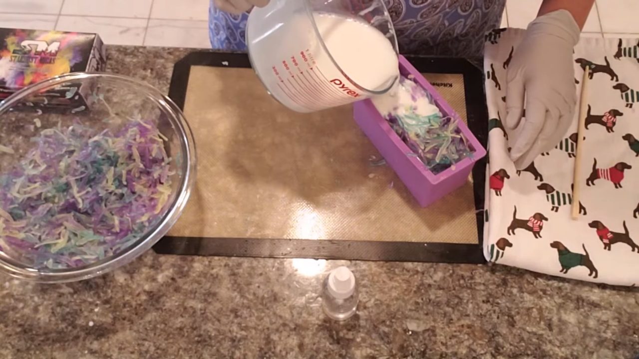 Pouring white melt and pour soap over the confetti in the loaf mold
