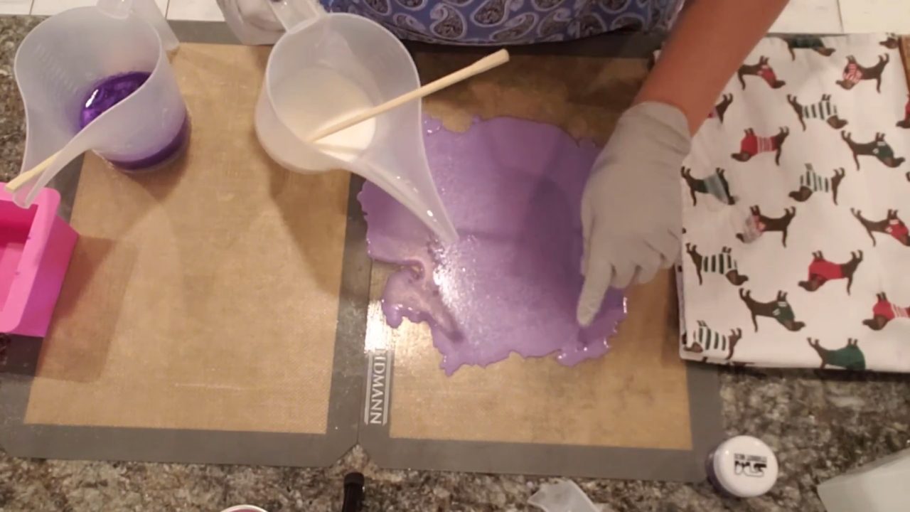 Pouring purple clear melt and pour soap onto a silicone mat