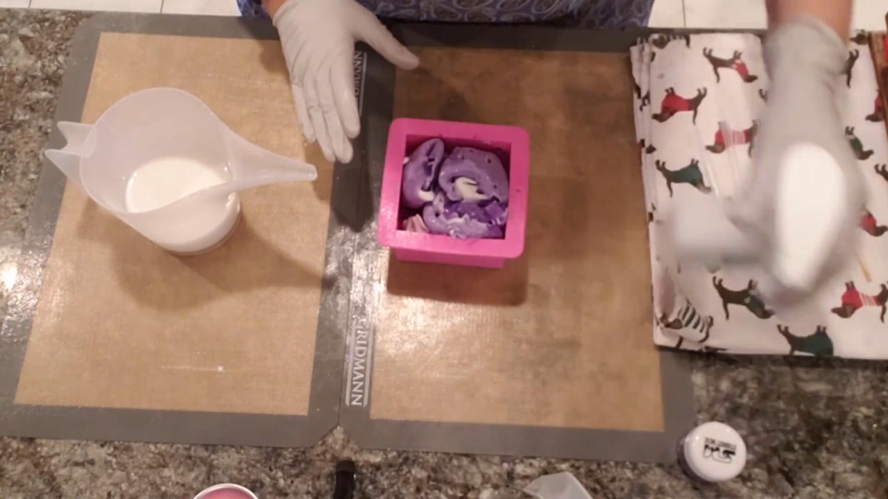 Pouring hot shea butter soap over the rolled layers in the mold