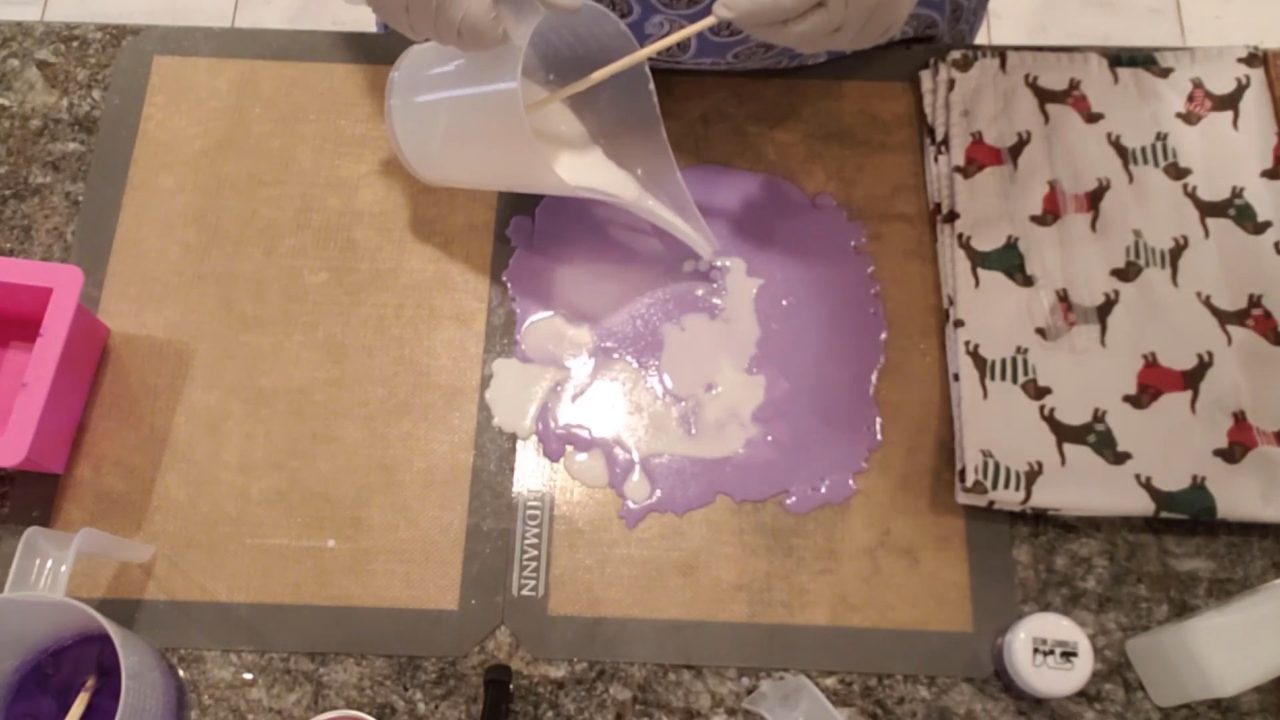 Pouring white shea butter soap over the purple layer