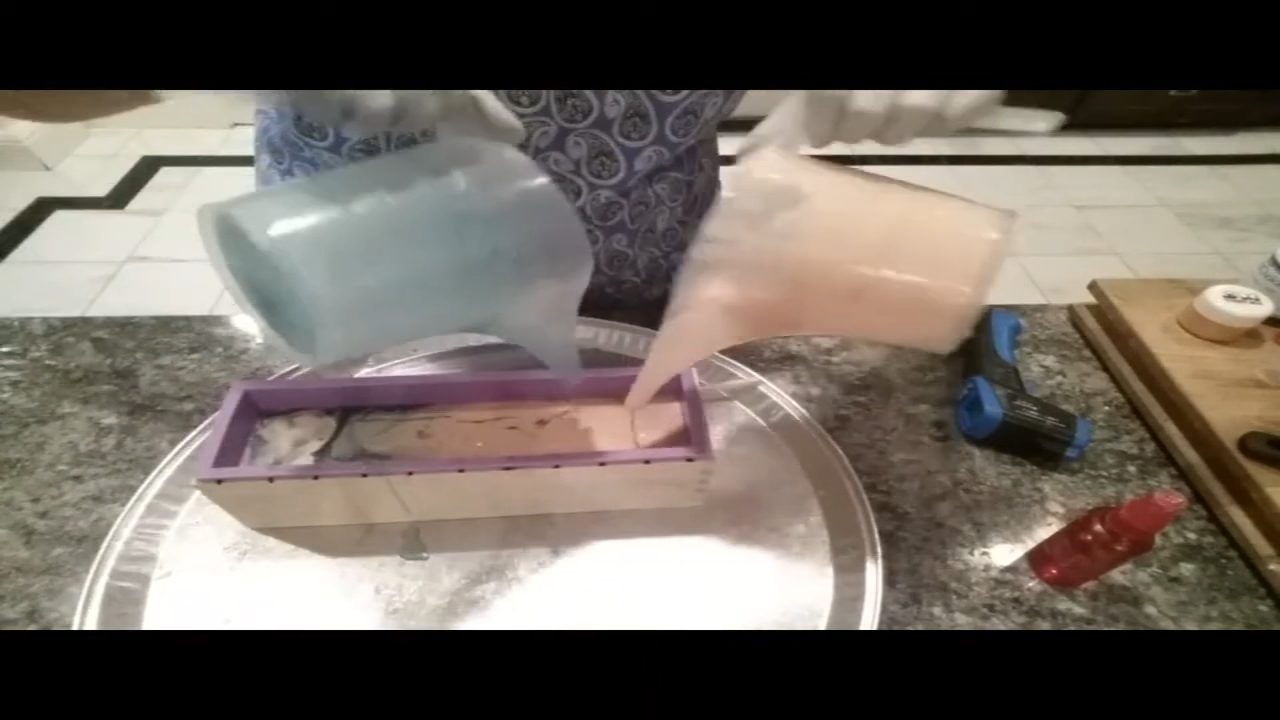 Pouring orange and green melt and pour soap together into a loaf mold