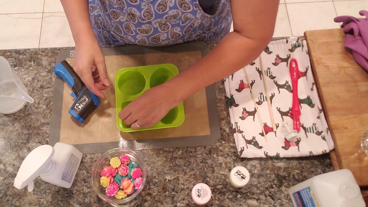 Placing mini rose embeds into clear melt and pour soap in a silicone mold