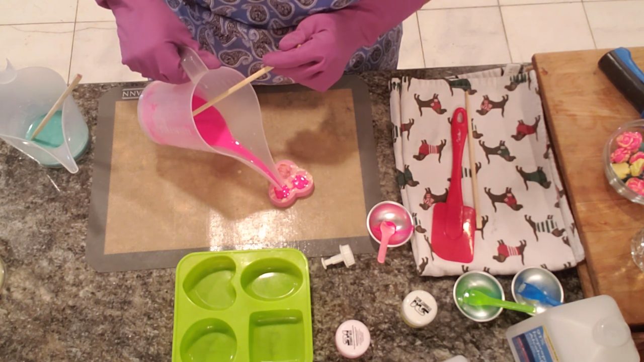 Pouring pink soap over the yellow in the rose mold