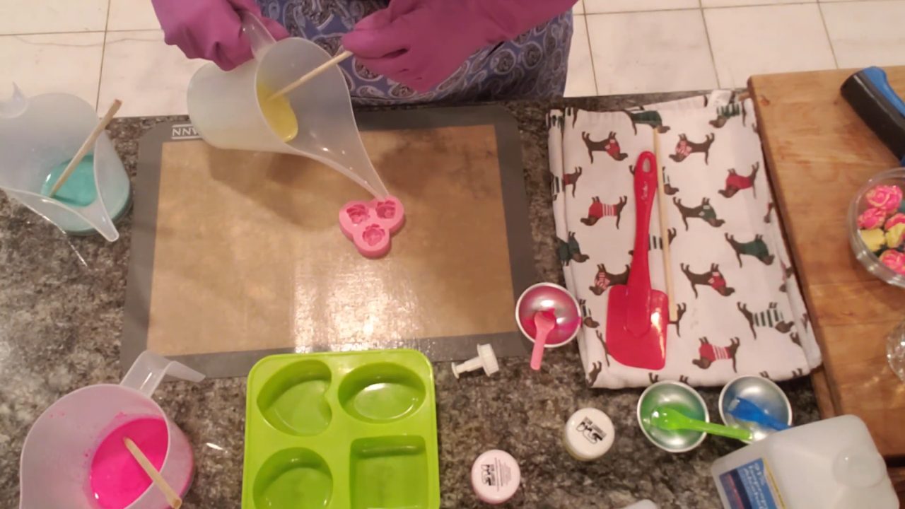 Pouring yellow avocado butter soap into a small rose silicone mold