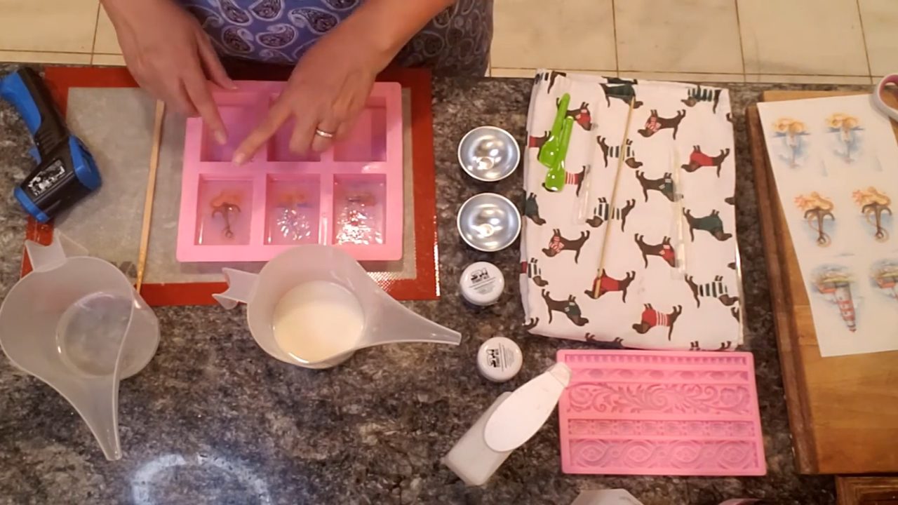 Pouring white shea butter soap behind the pictures in the mold