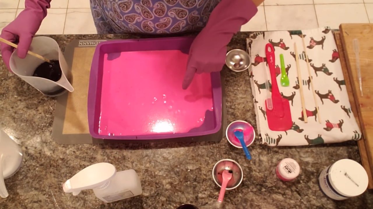 Pouring black charcoal clear soap over the pink layer