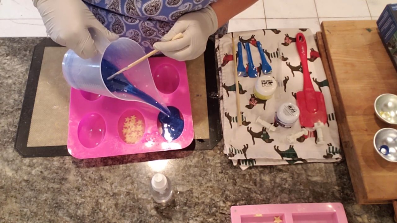 Pouring dark blue glitter soap behind the star embeds