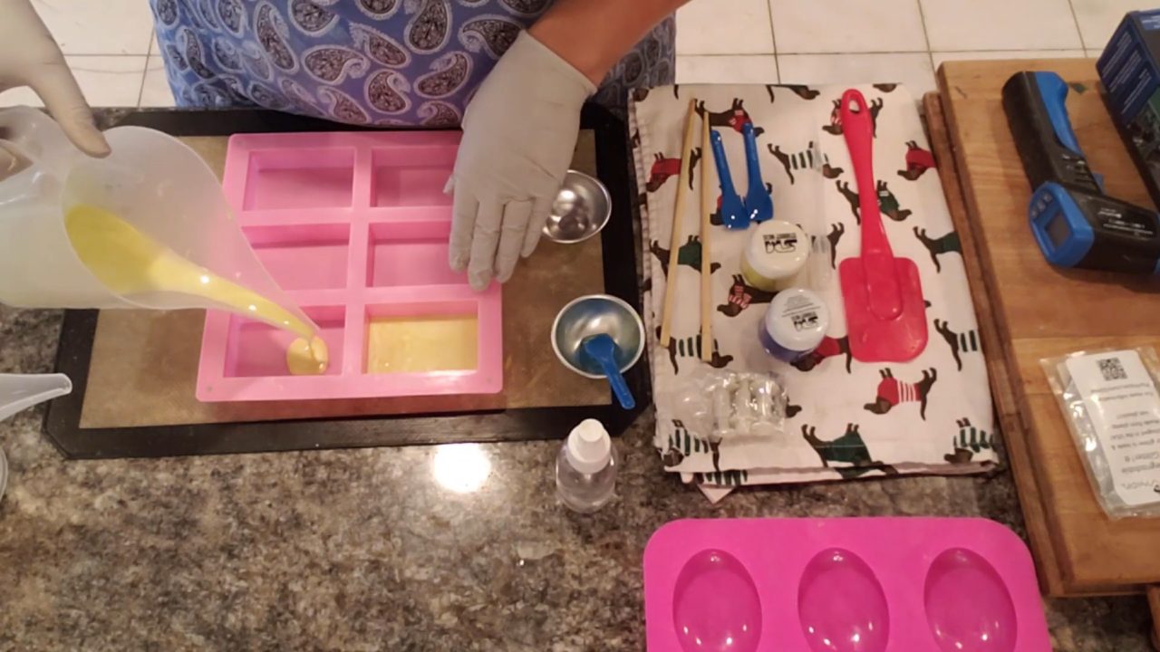 Pouring a thin layer of yellow shea butter soap into a rectangle mold