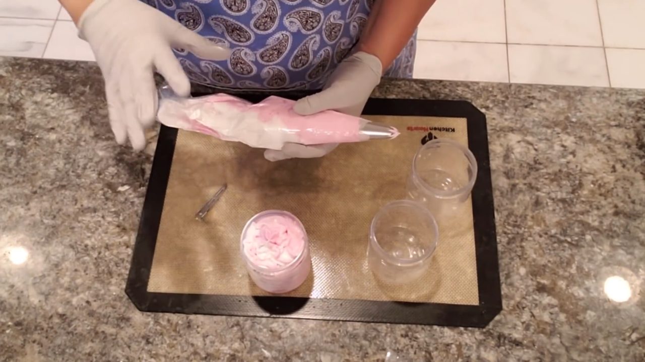 Piping red and white peppermint whipped soap into a jar