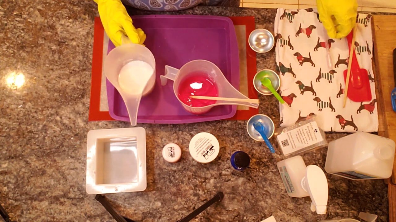 Pouring red mica-colored clear melt and pour soap into a silicone tray