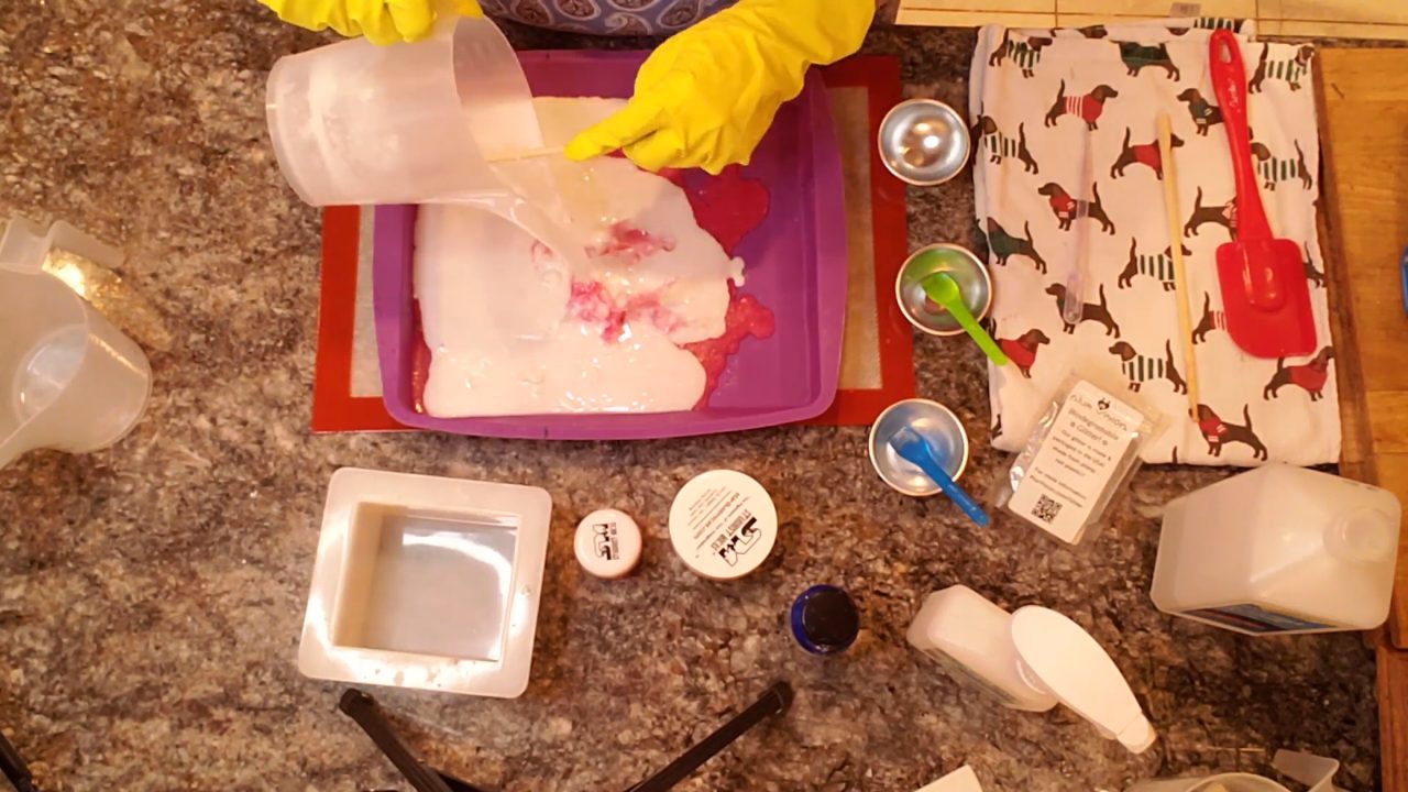 Pouring white shea butter melt and pour soap over the red layer