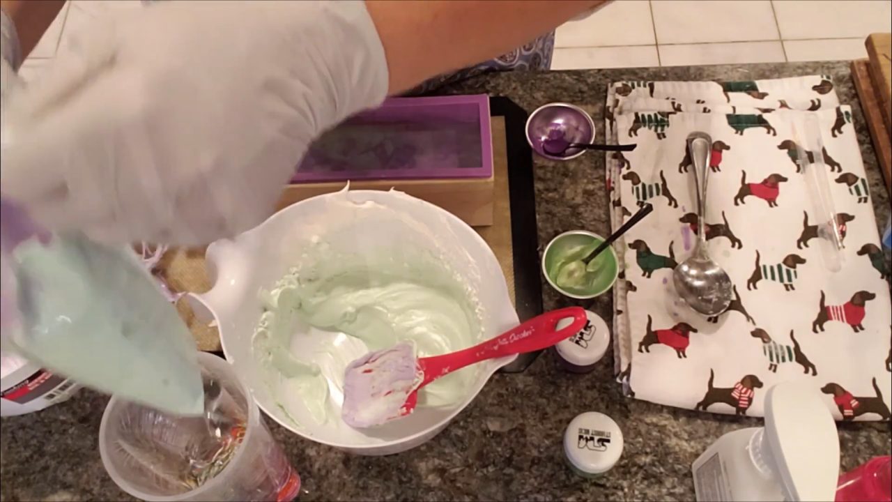 Piping green and purple soap frosting onto the soap loaf