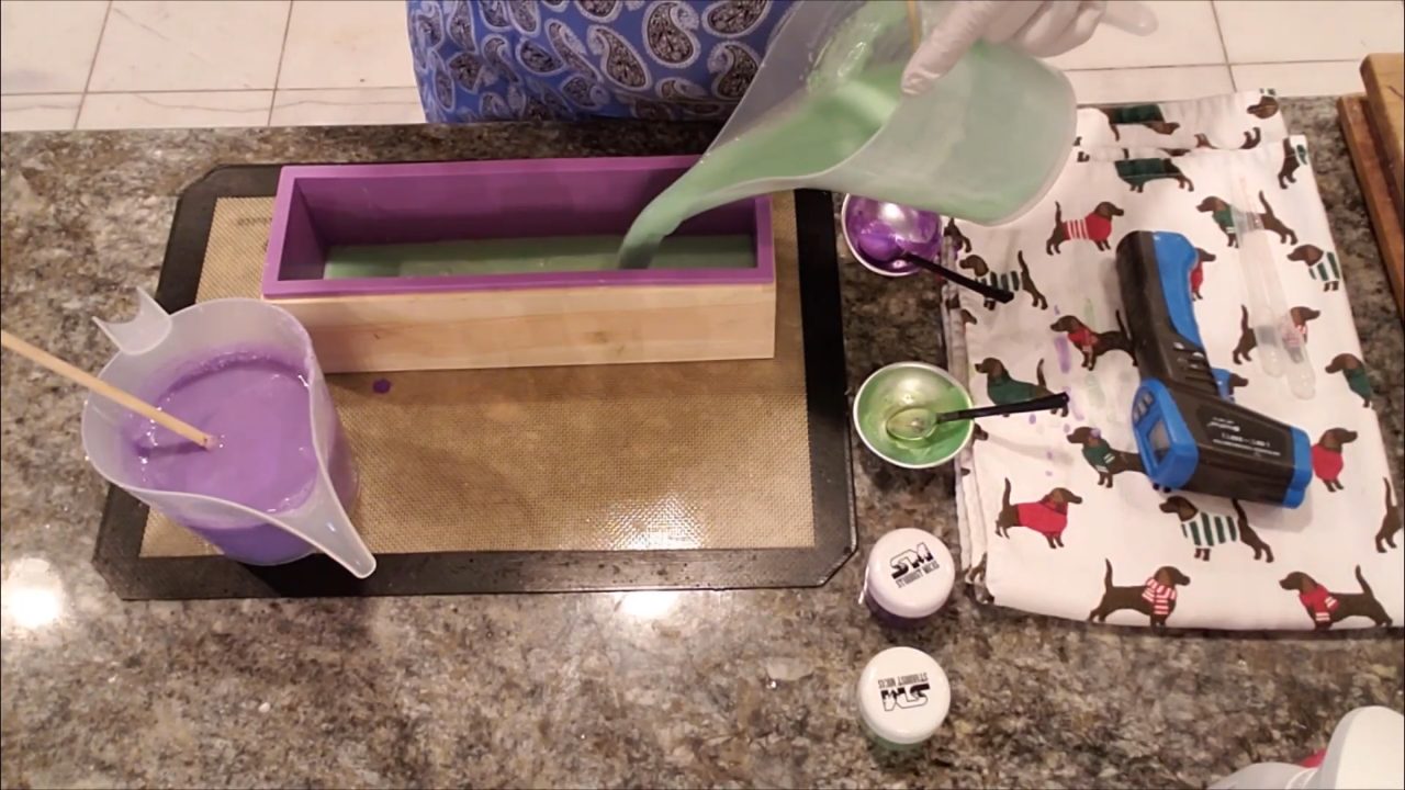 Pouring purple and green mica-colored melt and pour soap into a loaf mold