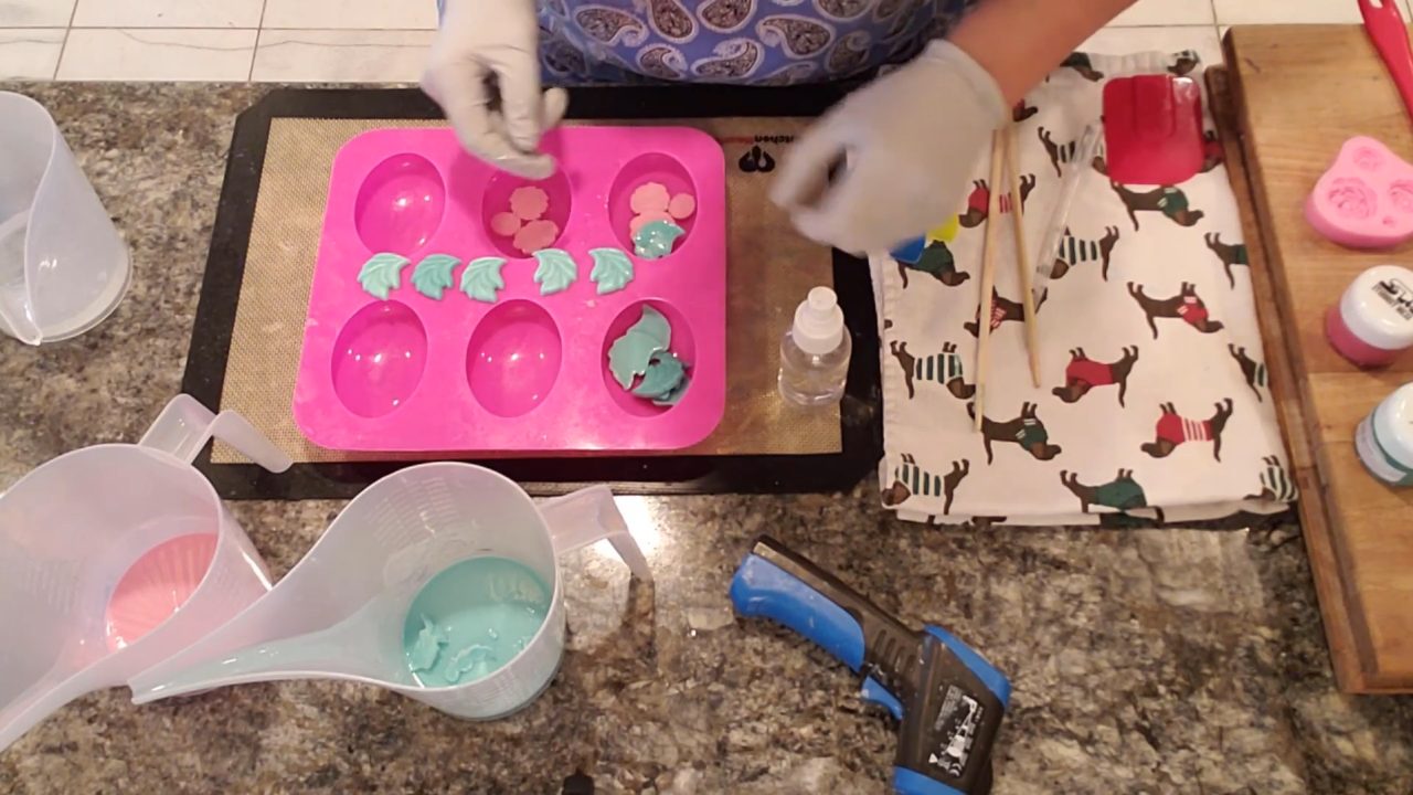 Arranging green soap leaves behind the roses in the oval mold