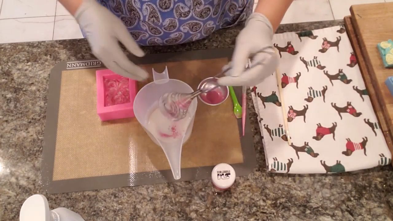 Pouring pink swirled shea butter soap into the rose mold